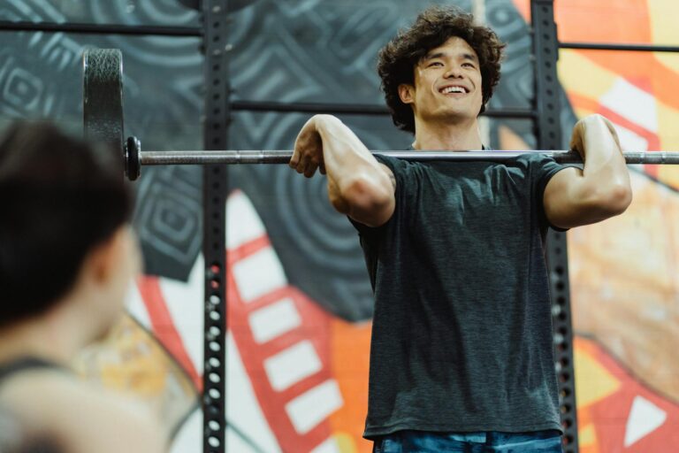 Young Asian man lifting a barbell indoors, showcasing strength and determination.