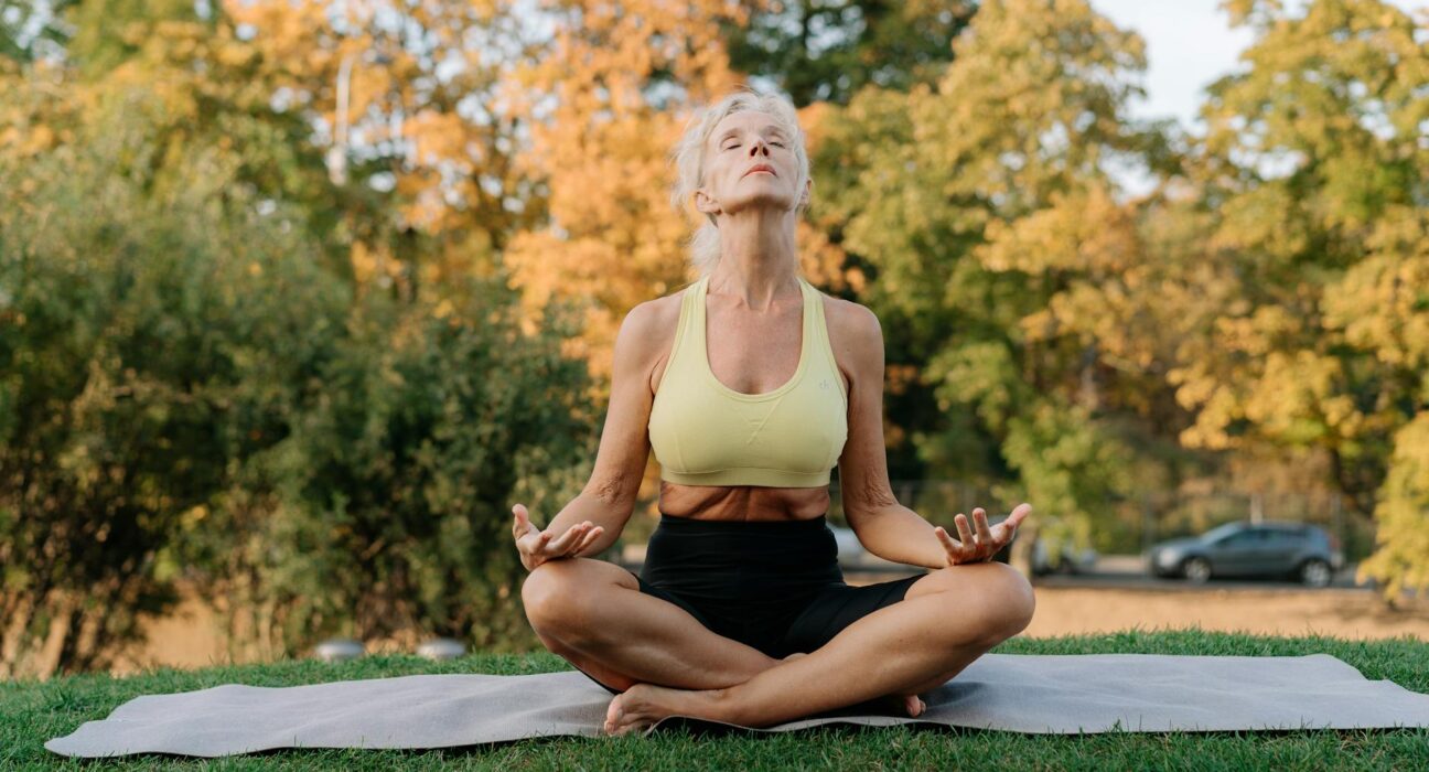 Serene senior woman practicing yoga outdoors, embracing a healthy lifestyle.