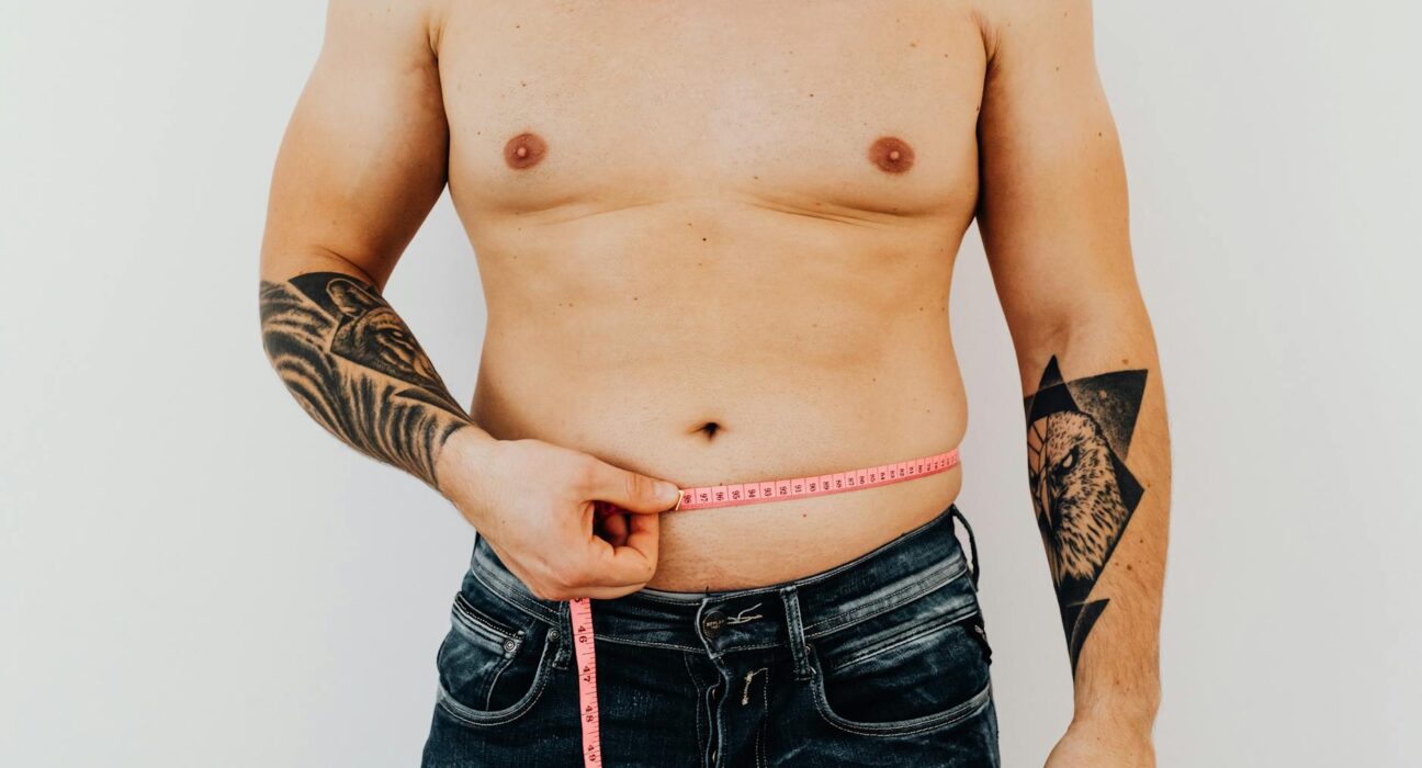 Man measuring his waist with tape, focused on fitness and weight management.