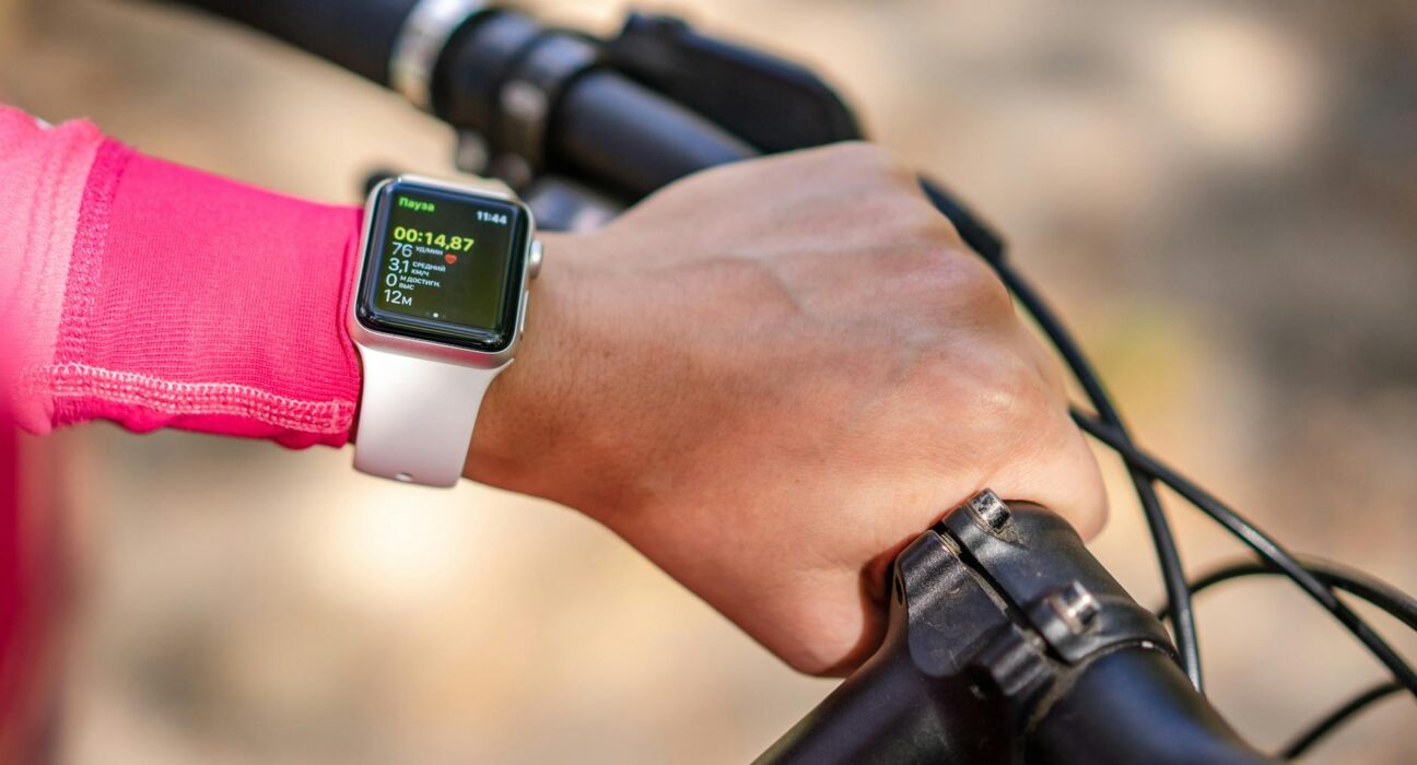 Cyclist checks smartwatch during bike ride. Focus on technology and fitness tracking.