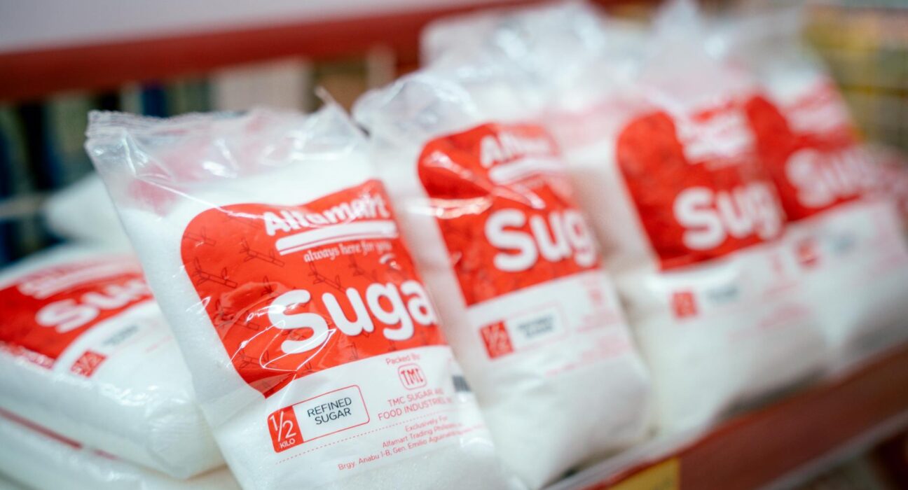 Close-up of sugar bags on a grocery store shelf, highlighting product packaging.
